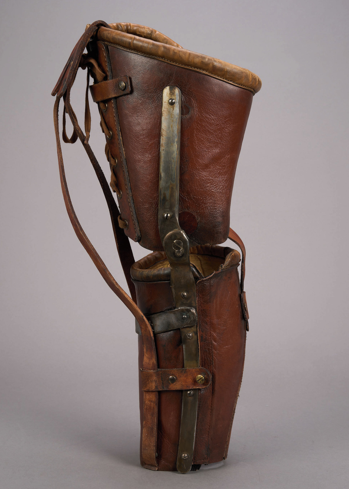 A brown-red leather leg brace displayed against a plain gray background.