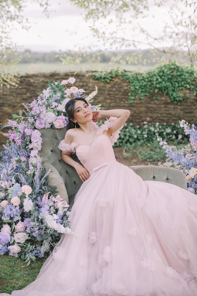 Woman in bridal dresses poses and looks off into the distance.