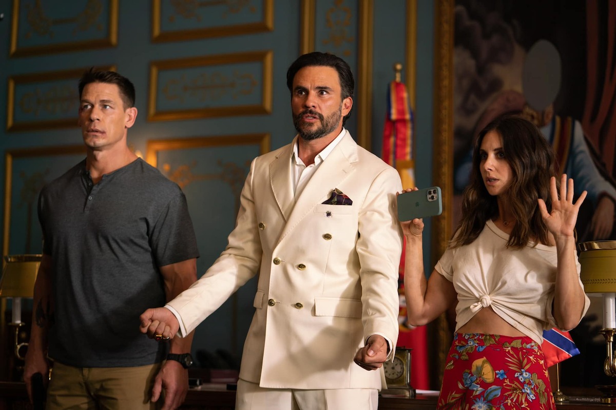 John Cena as Mason, Juan Pablo Raba as President Venegas, and Alison Brie as Claire attempt to diffuse a tense situation in a production still from ‘Freelance’.