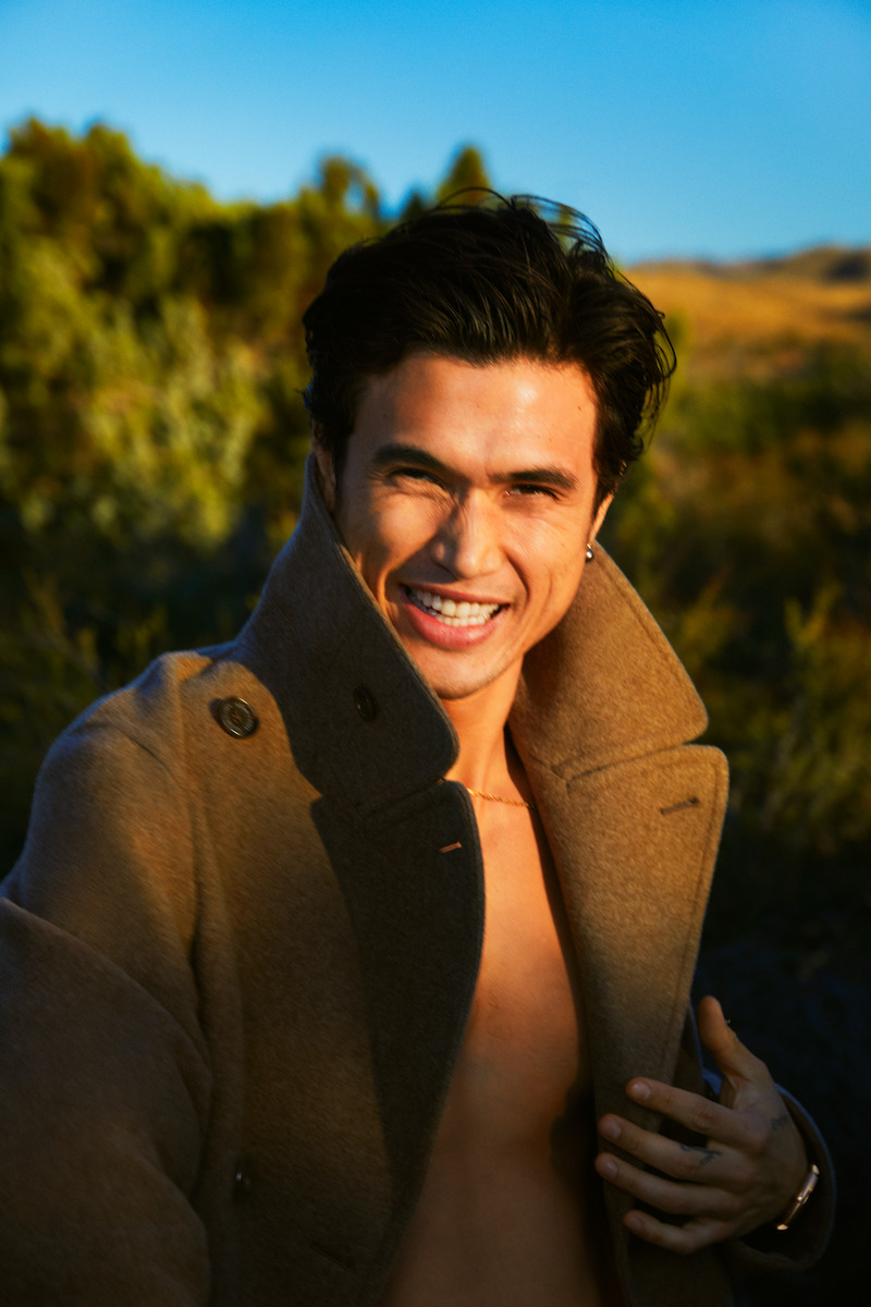 Charles Melton smiles with jacket open.