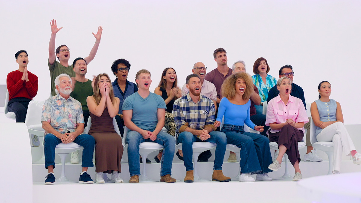 A diverse group of people sitting on white benches in a bright studio, displaying excitement and cheering as an audience, with various emotions and gestures visible.