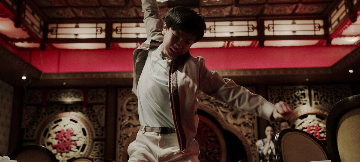 Isaac Wong as Young Charles Sun raises his arm for a fight in a grand restaurant in season 1 of ‘The Brothers Sun’