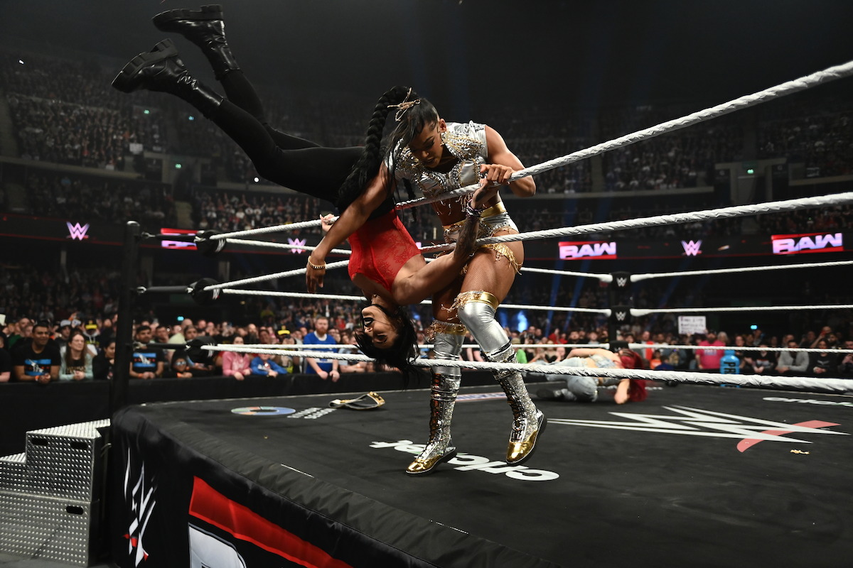 Bianca Belair throws Rhea Ripley out of the ring.