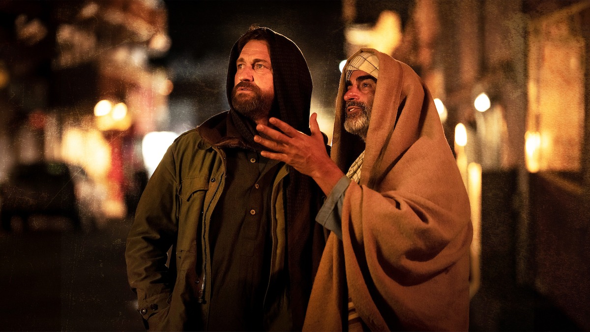 Gerard Butler as Tom with Navid Negahban as Mo observing a city square at night in a production still from ‘Kandahar.’