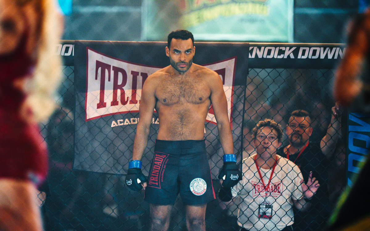 Lutador se posiciona no ringue de MMA para um combate enquanto o técnico o observa