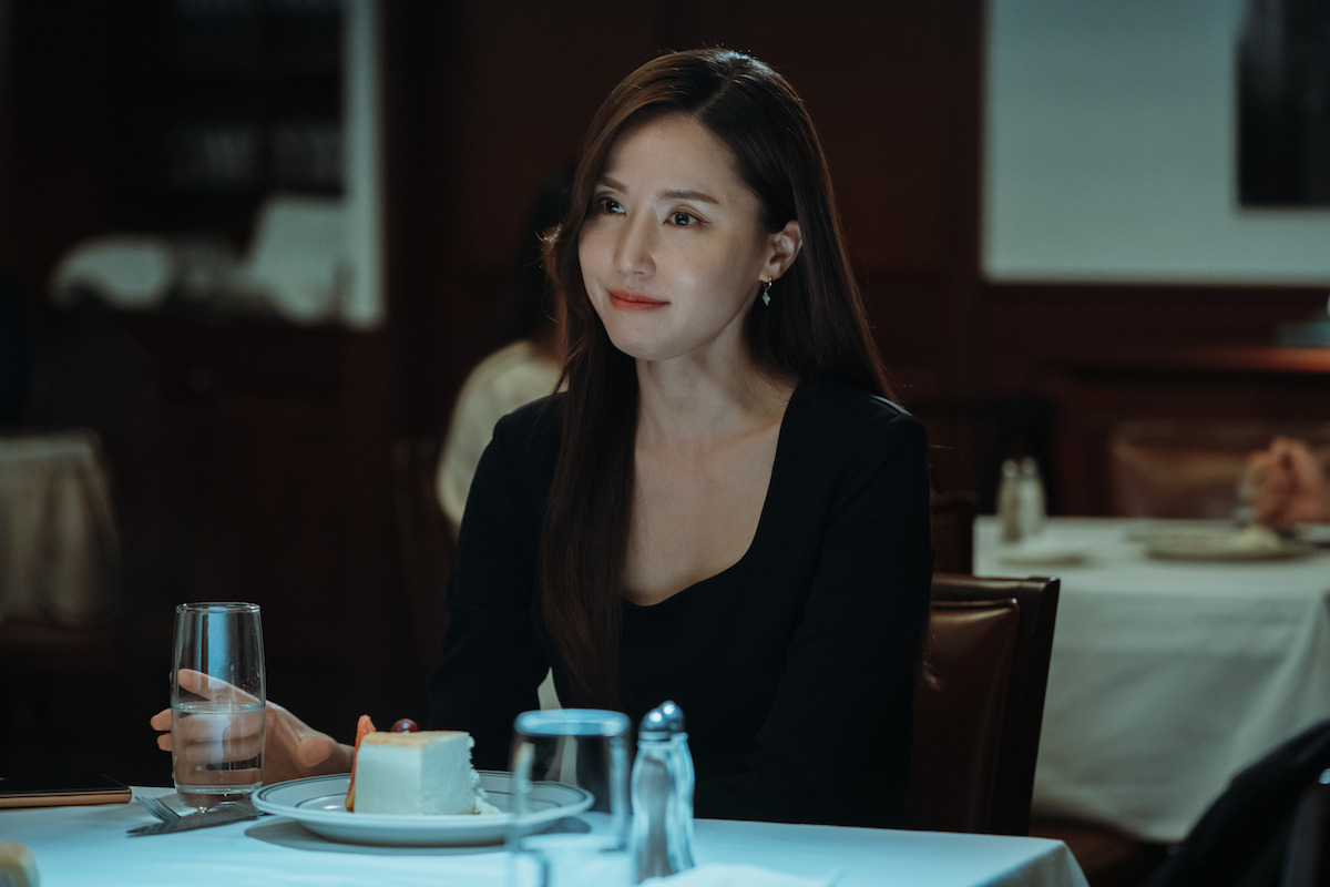 Kong Hyun-joo sits at a table at a restaurant wearing a black shirt while holding a glass of water in an image from ‘Weak Hero Class 1.’