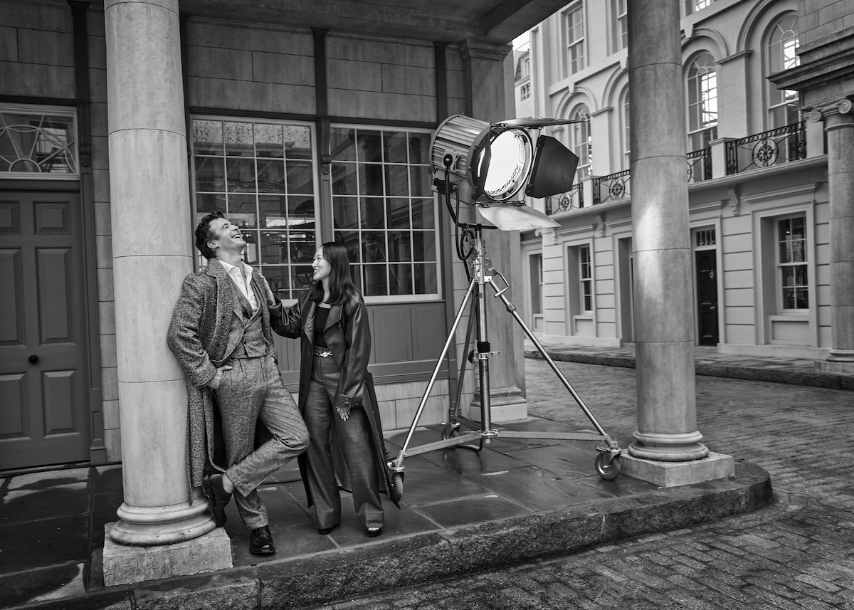 Black-and-white image of Luke Thompson and Yerin Ha standing together on a studio lot