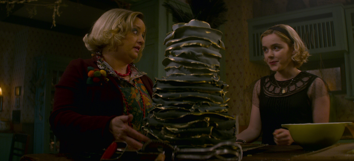 Chilling Adventures of Sabrina Sabrina and co-star standing in a dark room, talking next to a mysterious artifact.