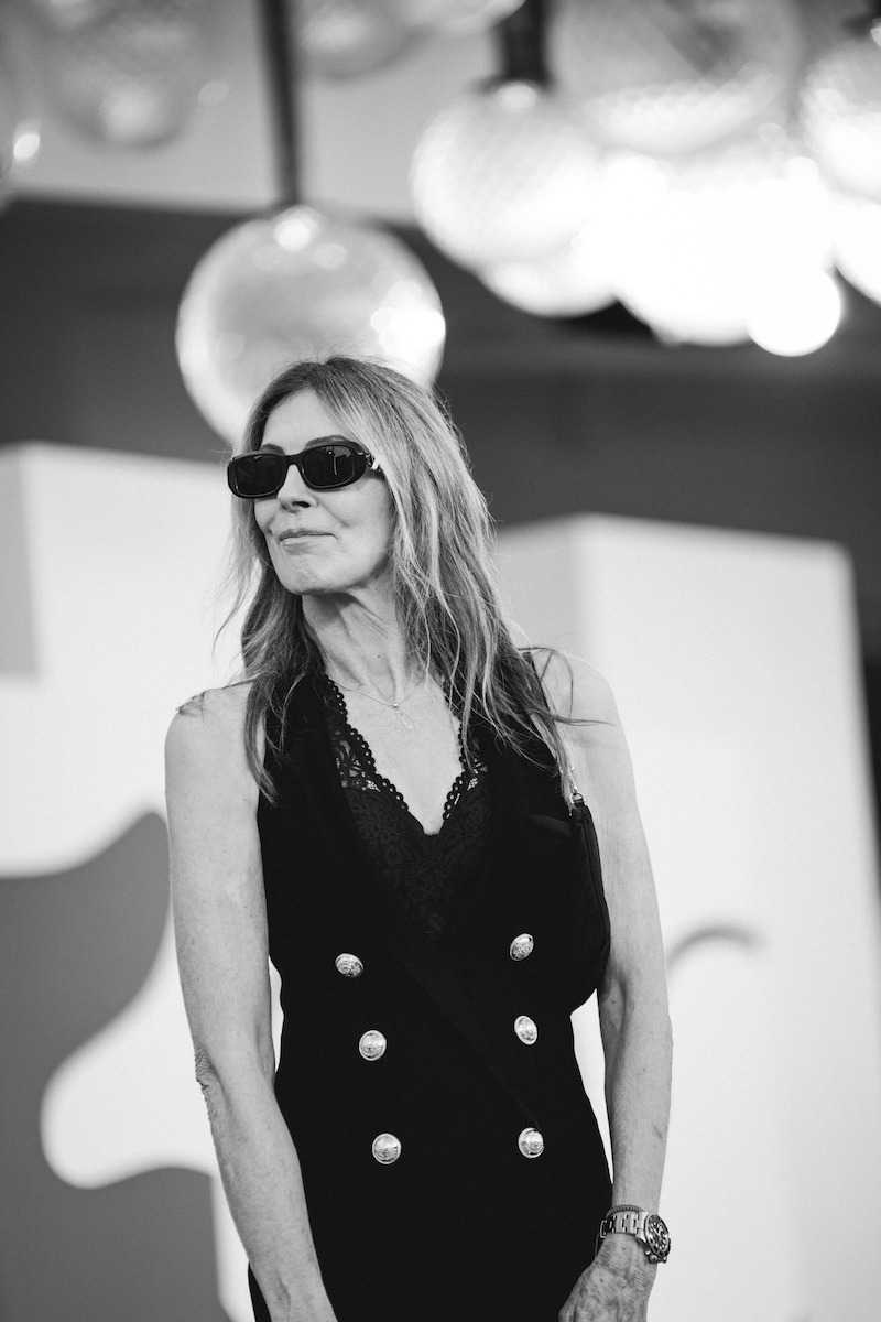 Kathryn Bigelow wears sunglasses and a black dress on the red carpet.