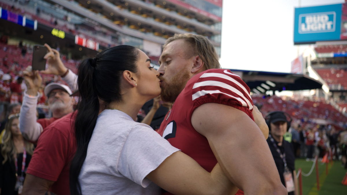Claire Kittle and George Kittle kiss after a game.