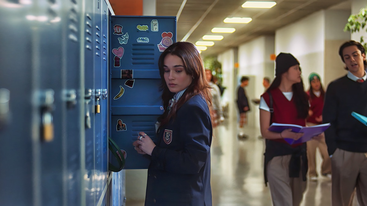 Eléa Rochera as Reese Russell holds a blue locker open in a school hallway while wearing a navy private-school uniform in an image from ‘Bad Influence.’