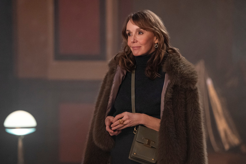 Philippine Leroy-Beaulieu as Sylvie Grateau smiles and wears a coat over her shoulders in Season 4 of 'Emily in Paris'