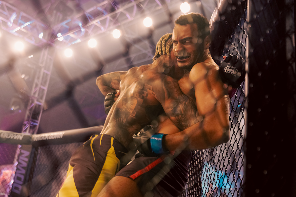 Dois lutadores, interpretados por Vinícius Neri e MC Cabelinho, se enfrentam num octógono de MMA