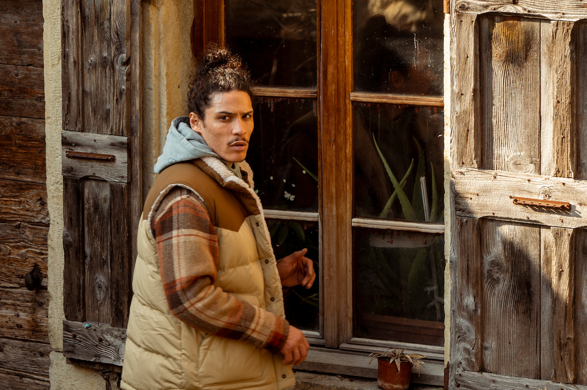 Hatik as Jaro Gatsi looks through the window of an old building in season1 of ‘Anthracite’