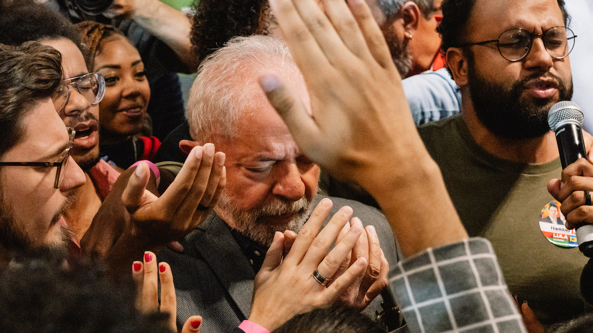 A crowd surrounds a man praying.
