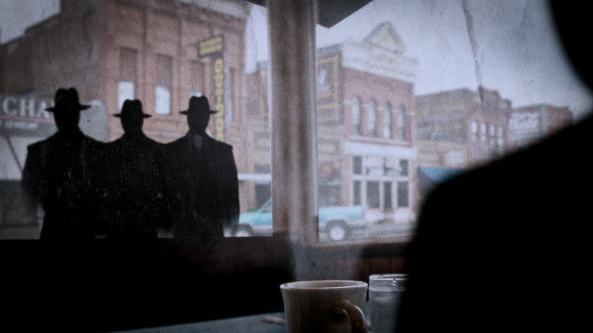Three shadowed men stare into a diner window in a still image from the series ‘Files of the Unexplained.’