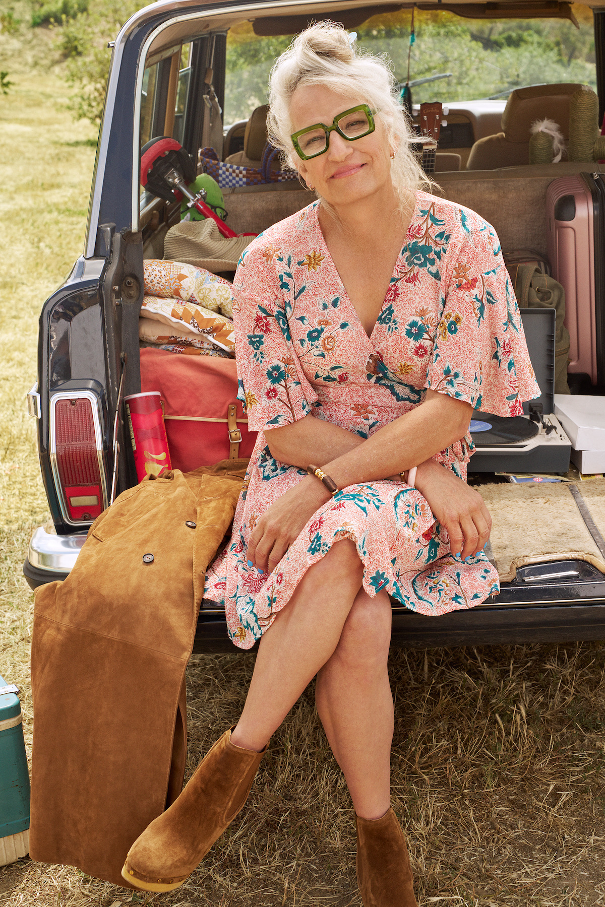 Harper Steele wears a flowered dress and sits in the back of a car smiling.