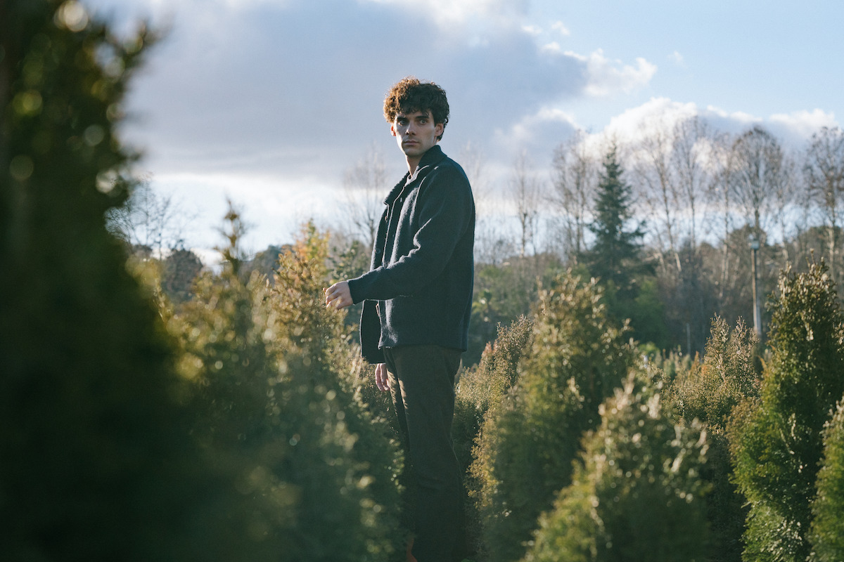 Álvaro Rico as Elmer stands among conifer trees in an image from ‘The Gardener.’