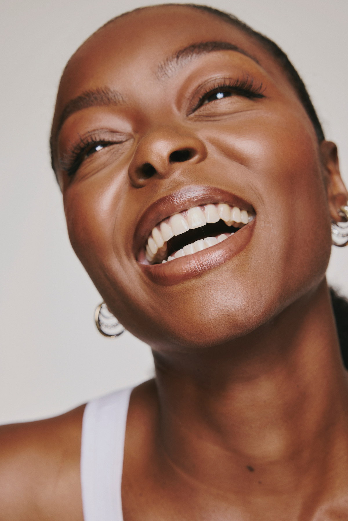 Danielle Deadwyler wears a white tank and smiles widely in this up-close shot.