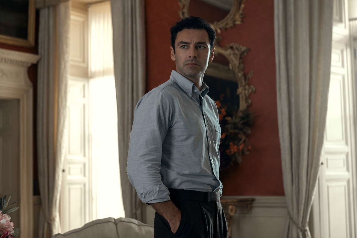 Aidan Turner as Callum Ellis stands with his hands in his pockets and looks over his shoulder pensively.