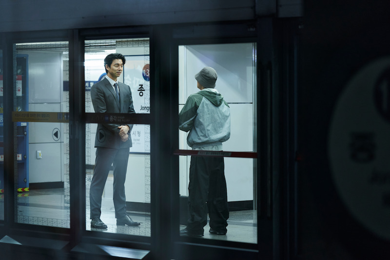 A man in a suit smiles as he talks with a man in sweats in 'Squid Game' Season 2 