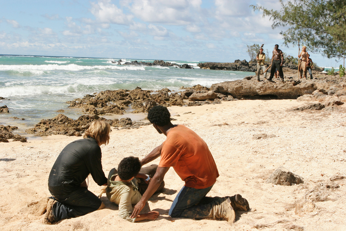 Josh Holloway and Harold Perrineau helping Daniel Dae Kim on the beach as Adewale Akinnuoye-agbaje and others approach.