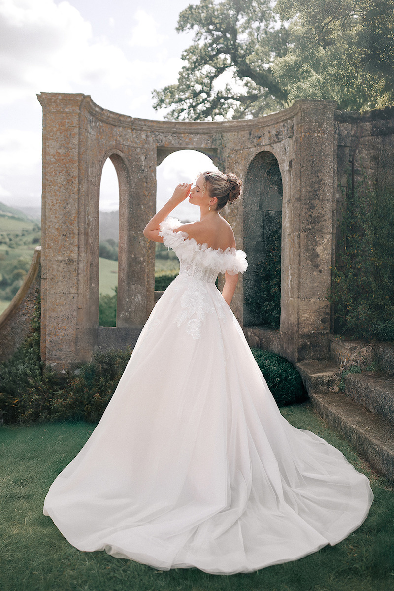 Woman in bridal dresses poses and looks off into the distance.