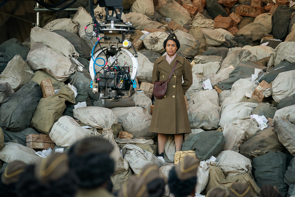 Behind the scenes of The Six Triple Eight with Kerry Washington. Washington wears her uniform and stands in front of a stone wall.