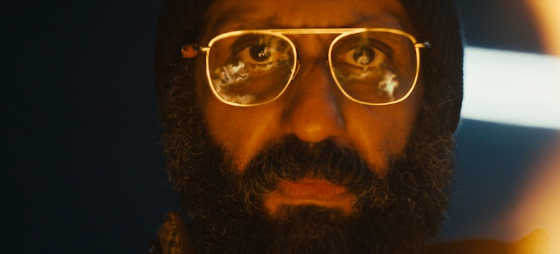 Adeel Akhtar as Singh with fire reflecting in his glasses in Season 3 of 'Sweet Tooth'