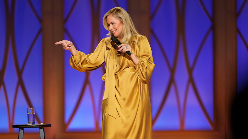 Leanne Morgan stands on stage holding a microphone.