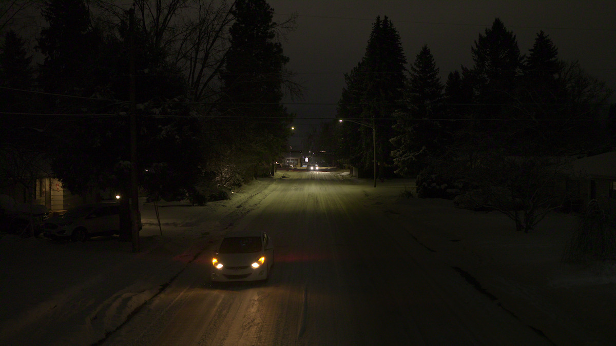 a car drives down a snowy street at night
