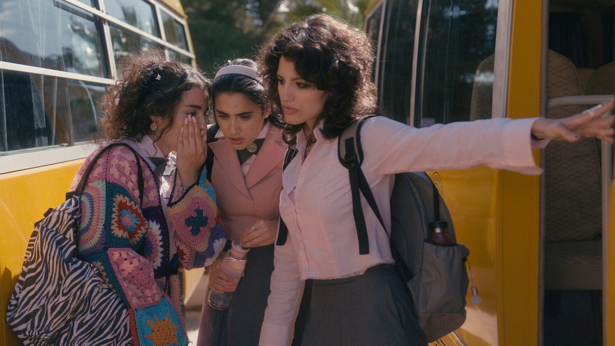 Sarah Abdelrahman as Tasneem, Kira Yaghnam as Hiba gather together outside of yellow busses in season 2 of ‘Al Rawabi School for Girls’