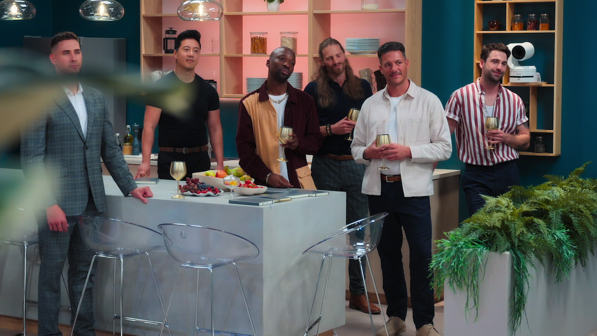 A group of singles standing in the kitchen.