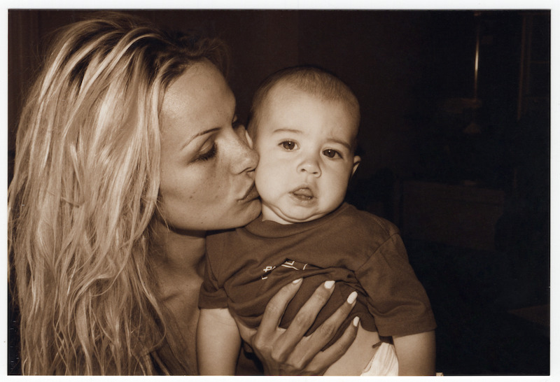 Pamela giving her infant son a kiss on the cheek.