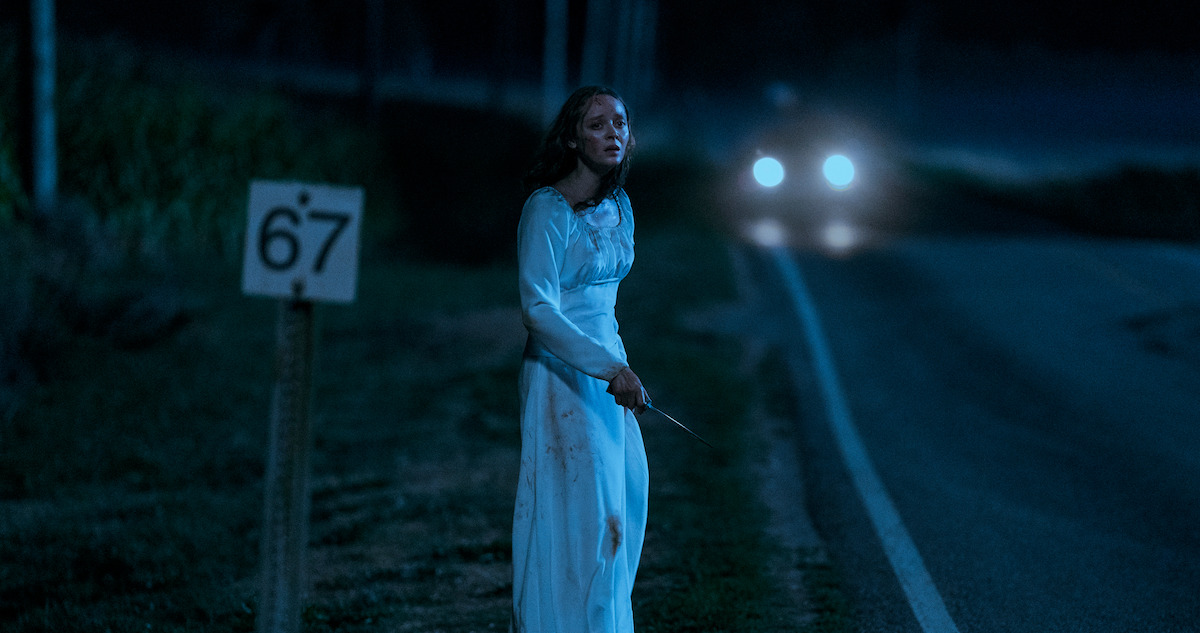 Madeleine Arthur as Mae stands by a country road at night in ‘Devin in Ohio’