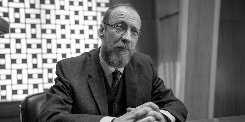 Black and white image of David Thewlis as Hades sitting at a desk in Season 1 of ‘Kaos’