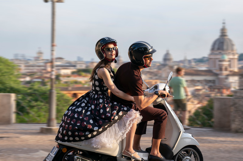 Lily Collins as Emily and Eugenio Franceschini as Marcello ride a scooter together in Season 4 of 'Emily in Paris'