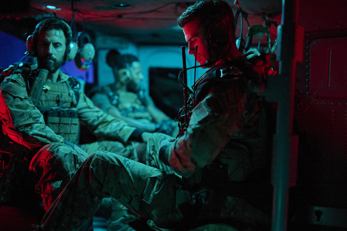 Liam Hemsworth as Sergeant JJ Kinney wears a military uniform while riding in a helicopter in ‘Land of Bad’