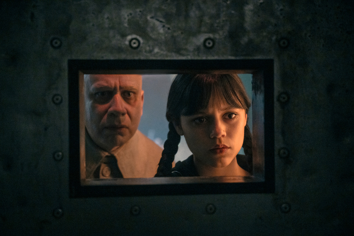 Fred Armisen as Uncle Fester and Jenna Ortega as Wednesday Addams look through a wicket in Willow Hill in ‘Wednesday’ Season 2.