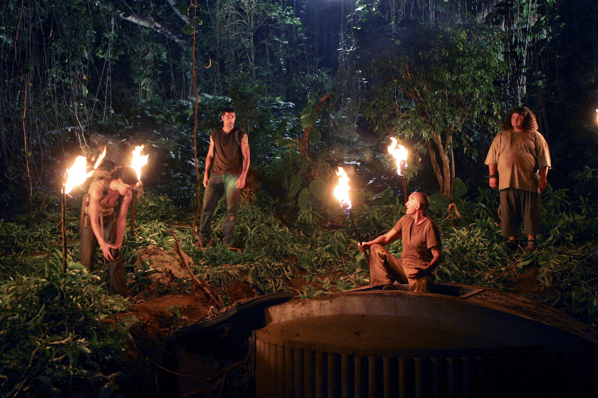 LOST, Evangeline Lilly, Matthew Fox, Terry O'Quinn, and Jorge Garcia standing around a hatch with torches burning in the jungle.