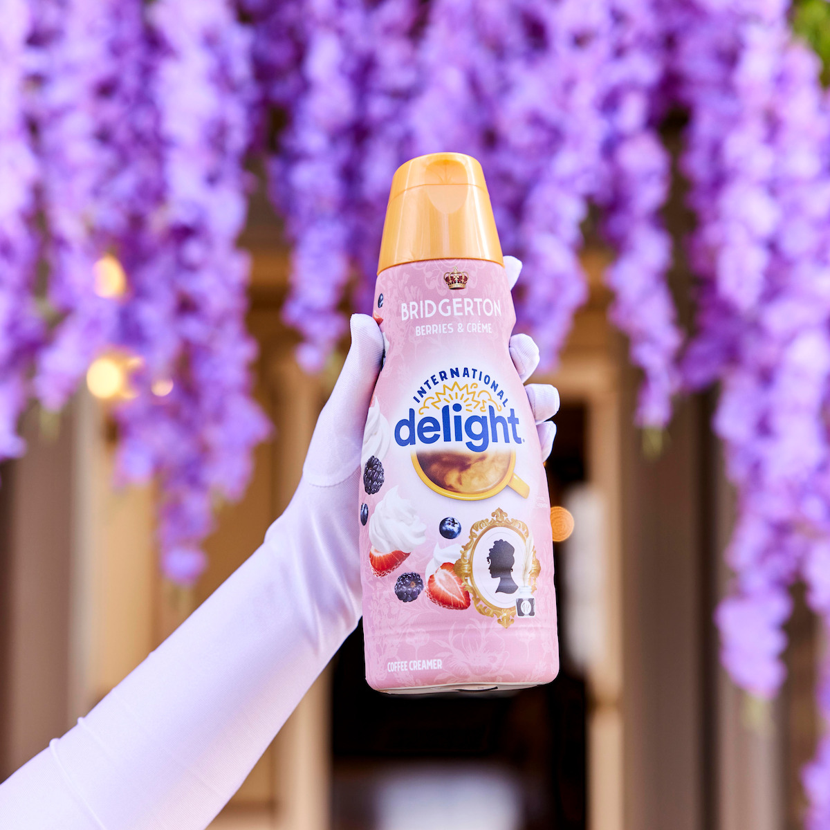 A hand with wearing a white glove holds out a bottle of creamer from the ‘Bridgerton’ collaboration International Delight