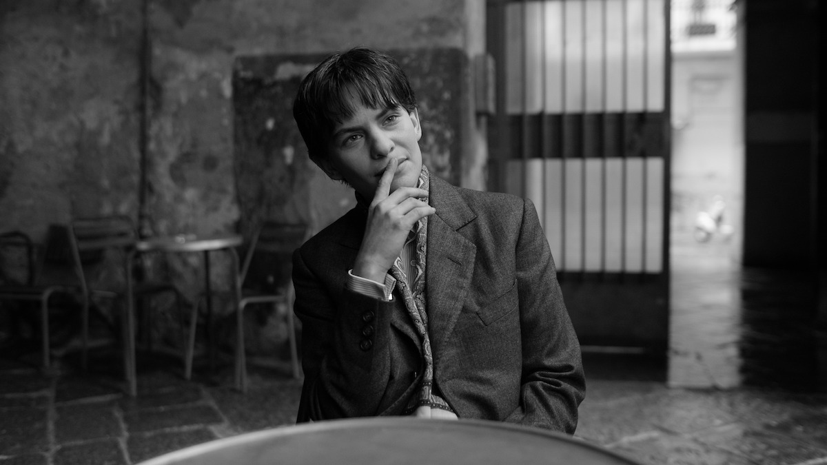 Eliot Sumner as Freddie Miles sits at a table in ‘Ripley’