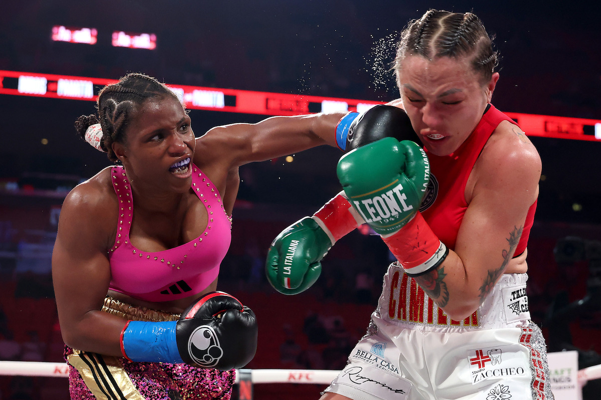 Caroline DuBois punches Camila Panatta during a heated match; one in a pink outfit lands a powerful punch on her opponent in red, with an audience and bright arena lights in the background.