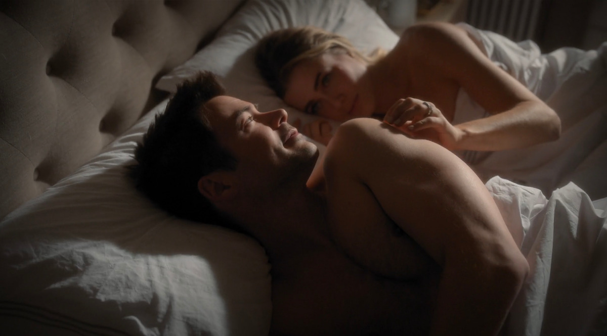 Two people cuddling in bed together.