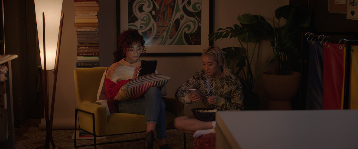 Hannah (Tati Gabrielle) and Liz (Soojeong Son) sitting in a room looking at tablets.