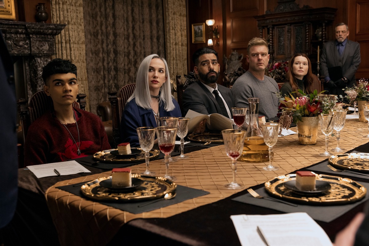 Sauriyan Sapkota as Prospero Usher, Kate Siegel as Camille L'Espanaye, Rahul Kohli as Napoleon Usher, Matt Biedel as Bill-T Wilson, Samantha Sloyan as Tamerlane Usher, and Mark Hamill as Arthur Pym sit at a dinner table together in ‘The Fall of the House of Usher.’ 