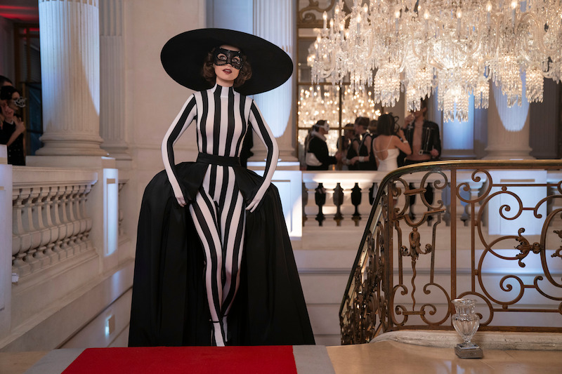 Lily Collins as Emily climbs a grand staircase wearing a black and white gown with a masquerade mask in Season 4 of 'Emily in Paris'