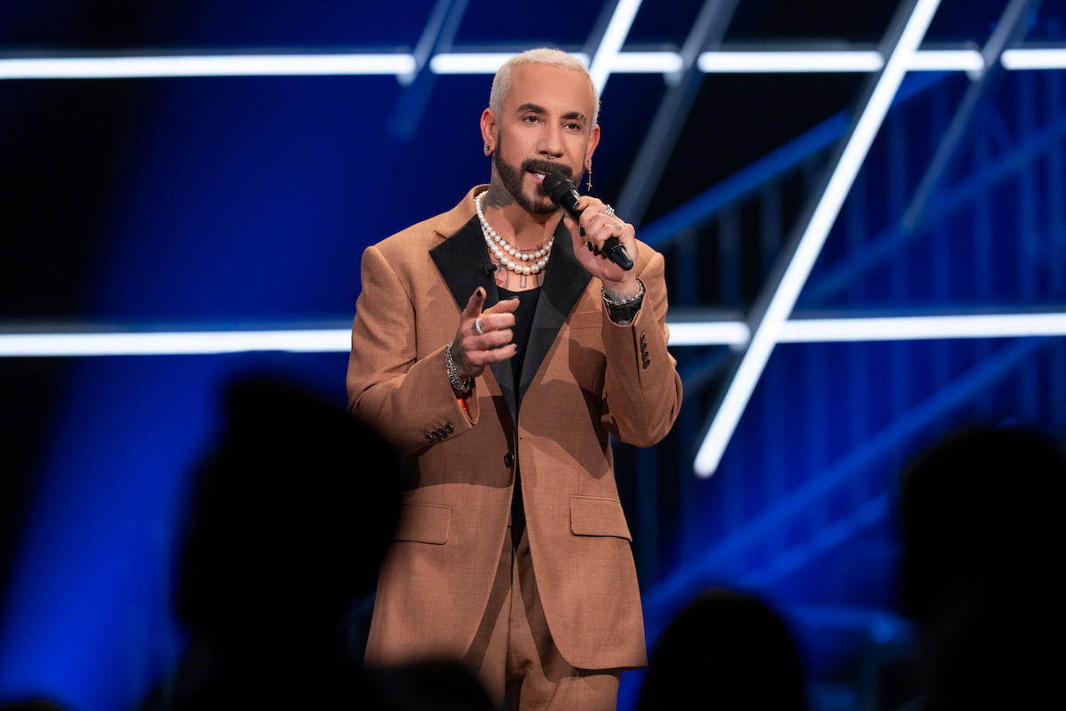 AJ McLean holding a microphone as he speaks to a crowd.