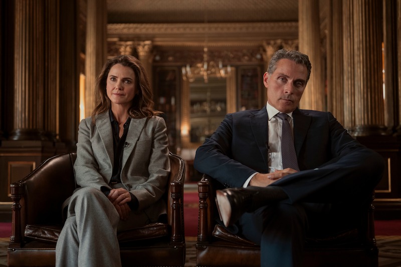 Keri Russell as Kate Wyler and Rufus Sewell as Hal Wyler seated in chairs of a grand room in Episode 305 of 'The Diplomat.'