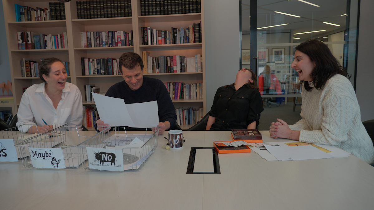 Thee staff laughs as they choose a cartoon.